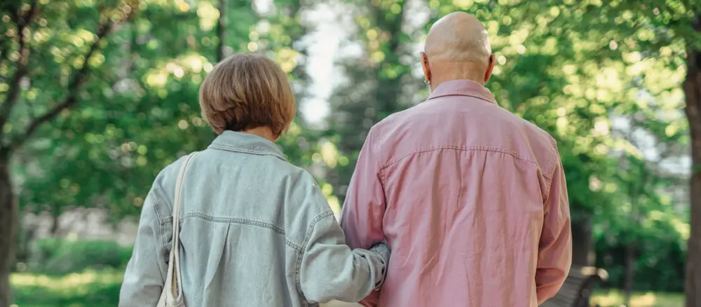 An older couple walking together outdoors.