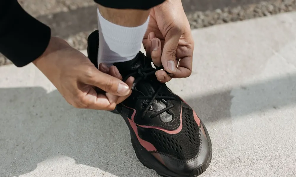 A person fastening a sneaker before heading out.