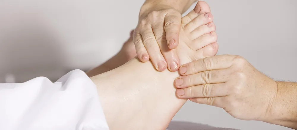Hands holding a bare foot during manual treatment.