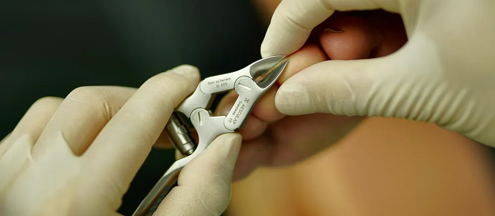 A gloved hand using a nail instrument.